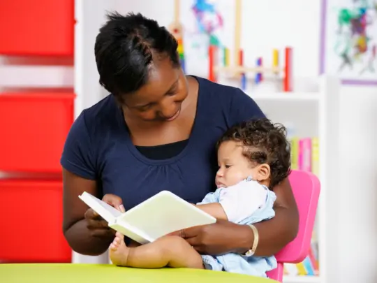 Carer/ Childminder/Teacher Reading With A Young Baby