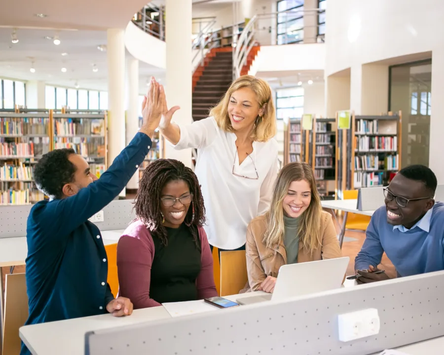 Cheerful multiethnic students having high five with teacher